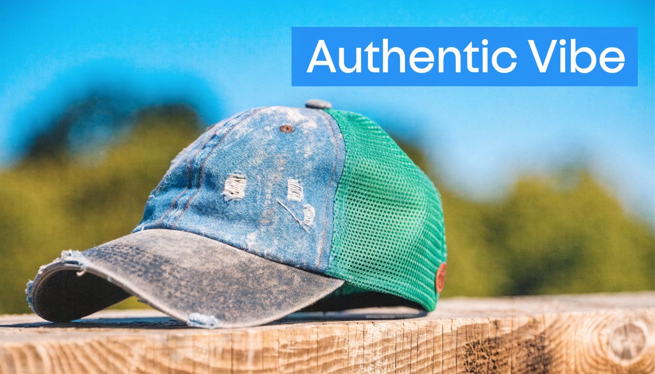 A distressed blue denim and green mesh trucker hat resting on a wooden surface outdoors.