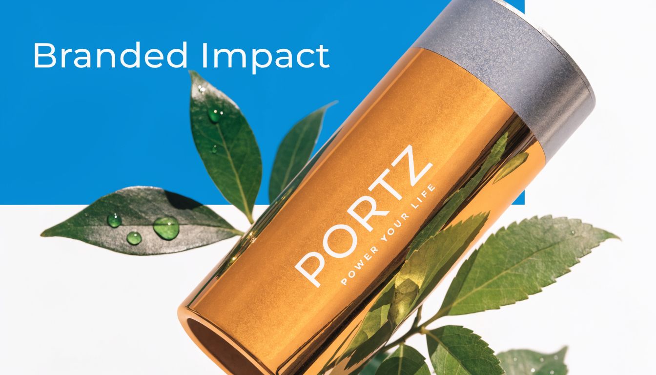 A golden Portz branded portable power bank displayed elegantly alongside fresh green leaves on a white background.