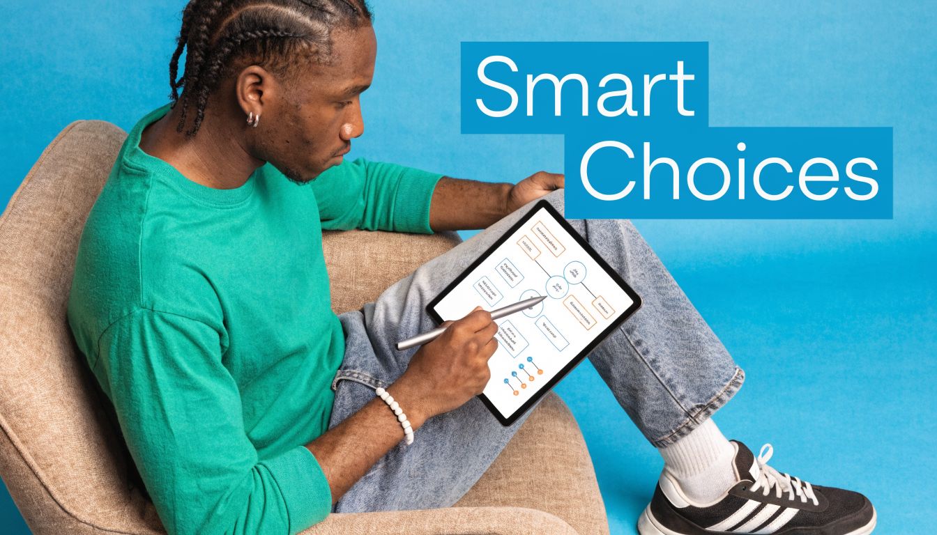 A young man sitting in an armchair using a digital stylus on a tablet showing charts.