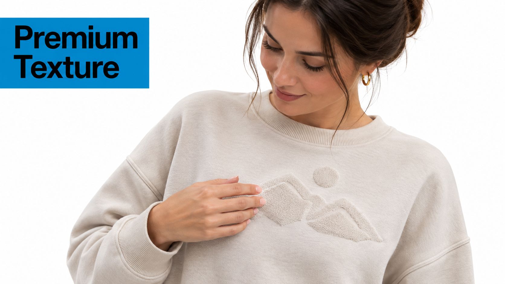 A woman wearing a beige sweatshirt with a textured embroidered mountain design on the chest area.